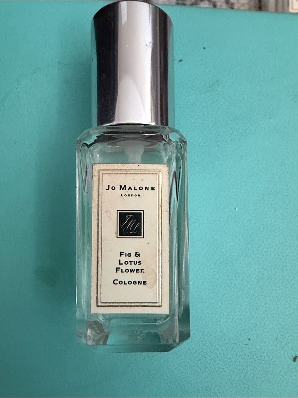 Jo Malone Clear Glass Cologne Bottle with Silver Cap on Teal Mat
